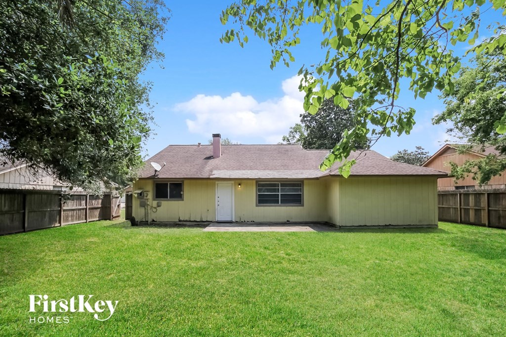 a small yellow house with a yard and a fence