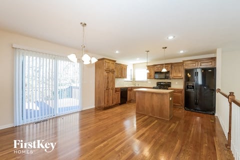 a kitchen with wood floors and wooden cabinets and a black refrigerator
