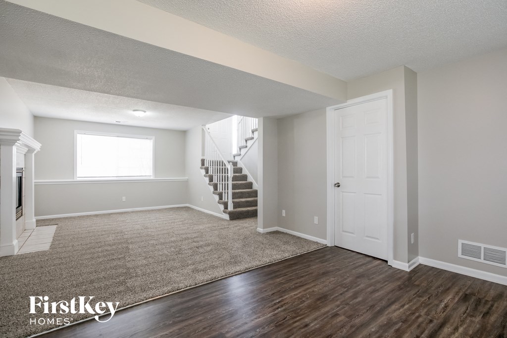 an empty living room with a door to a staircase