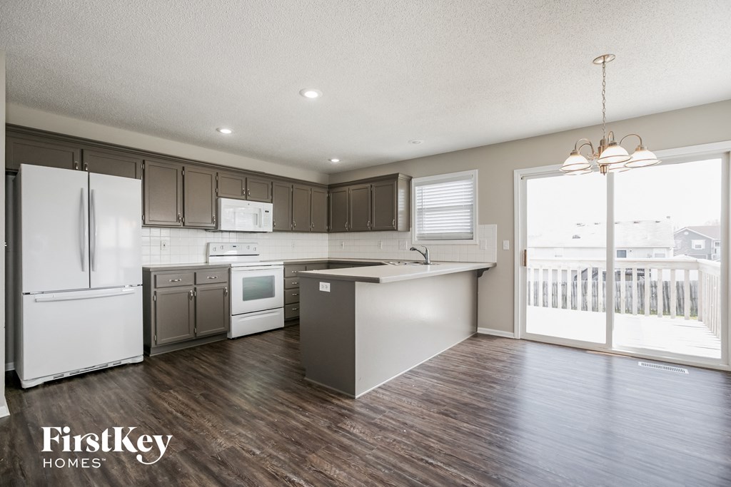 a kitchen with white appliances and wooden floors and a door to a balcony