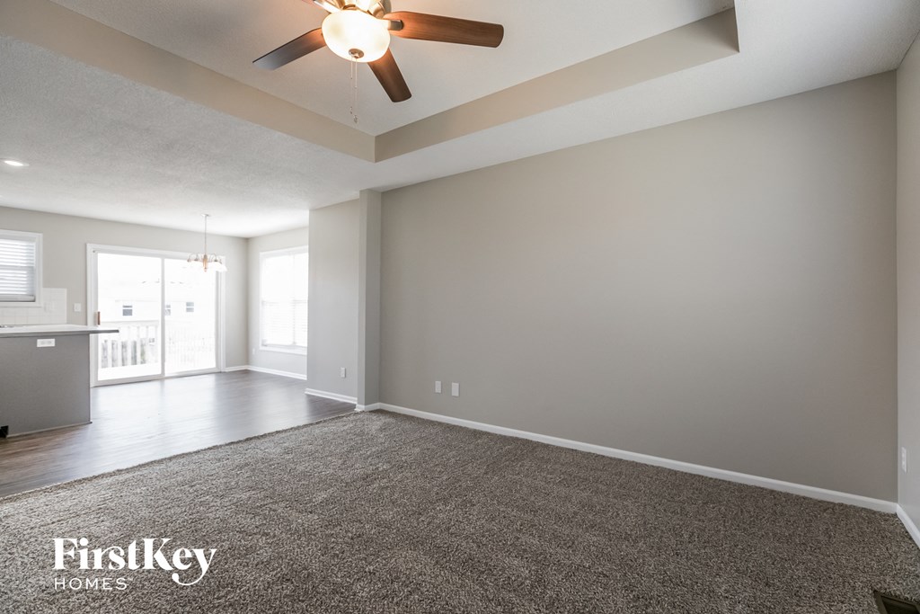 an empty living room with a ceiling fan and a rug
