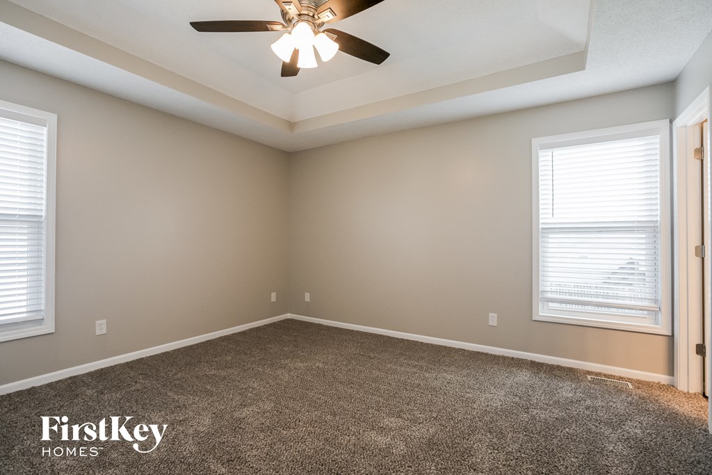 the master bedroom has a carpeted floor and a ceiling fan