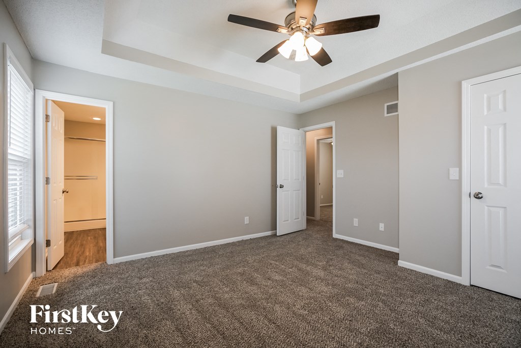a living room with a ceiling fan and a carpet
