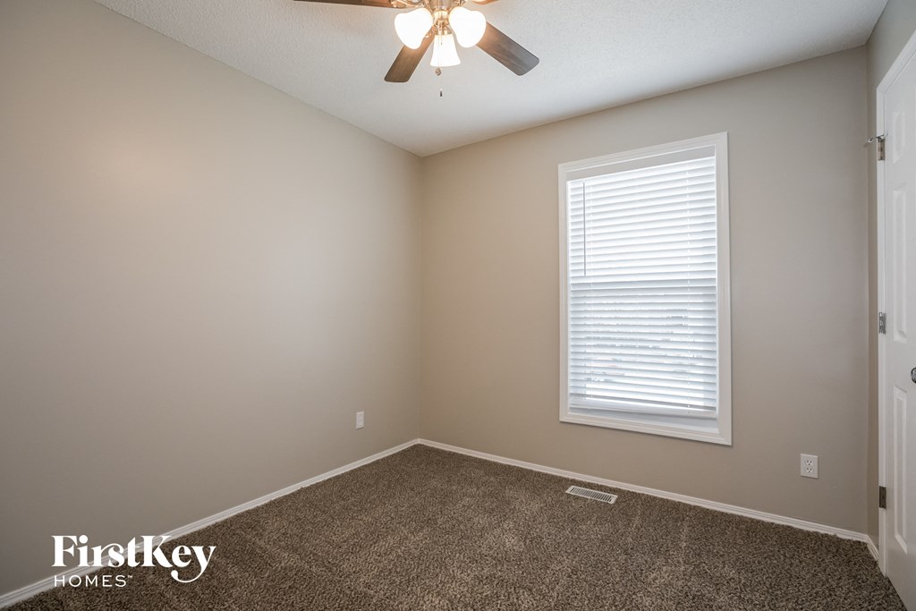 a empty room with a ceiling fan and a window