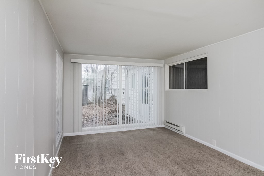 a living room with a large window and a carpeted floor