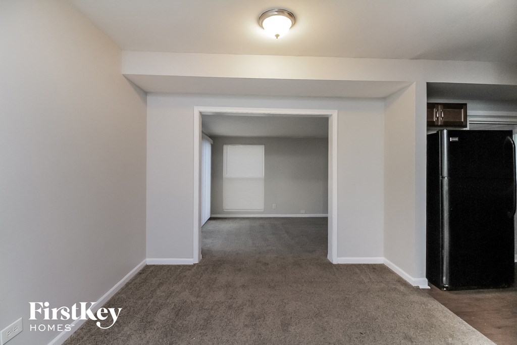 a living room with a carpeted floor and a black refrigerator