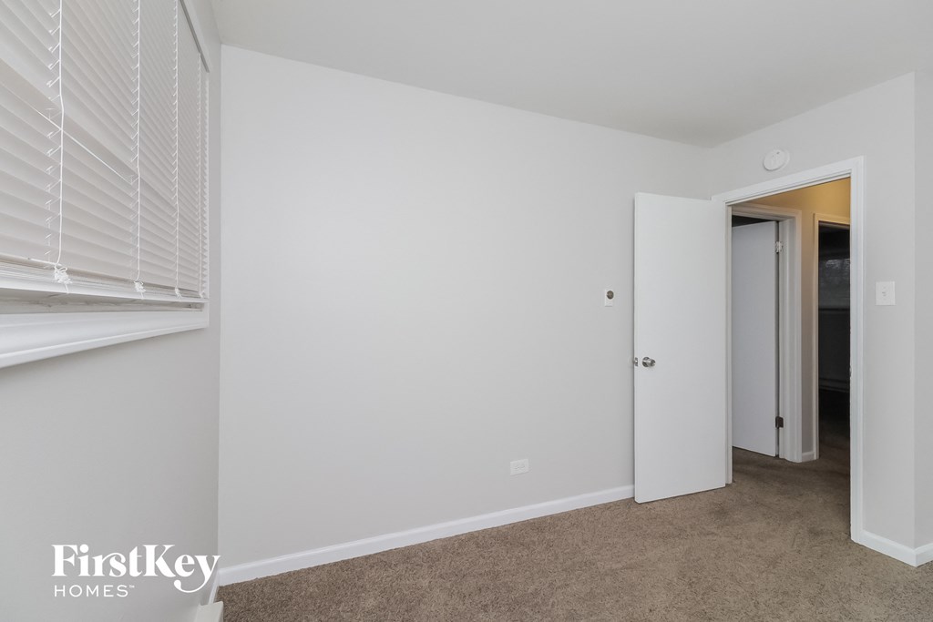 a bedroom with white walls and a door to a closet