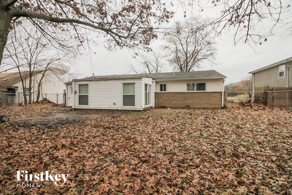 a small white house in a yard with fallen leaves