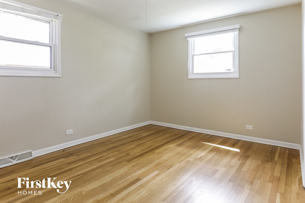 the living room of a home with wood flooring and two windows