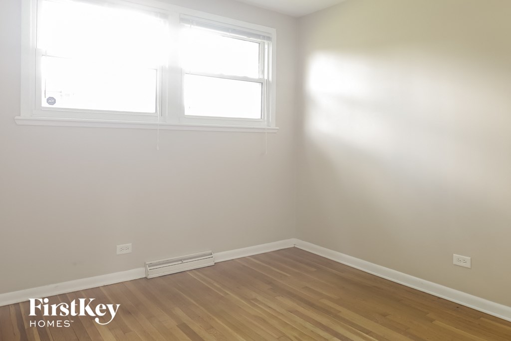 the corner of a room with two windows and a wooden floor