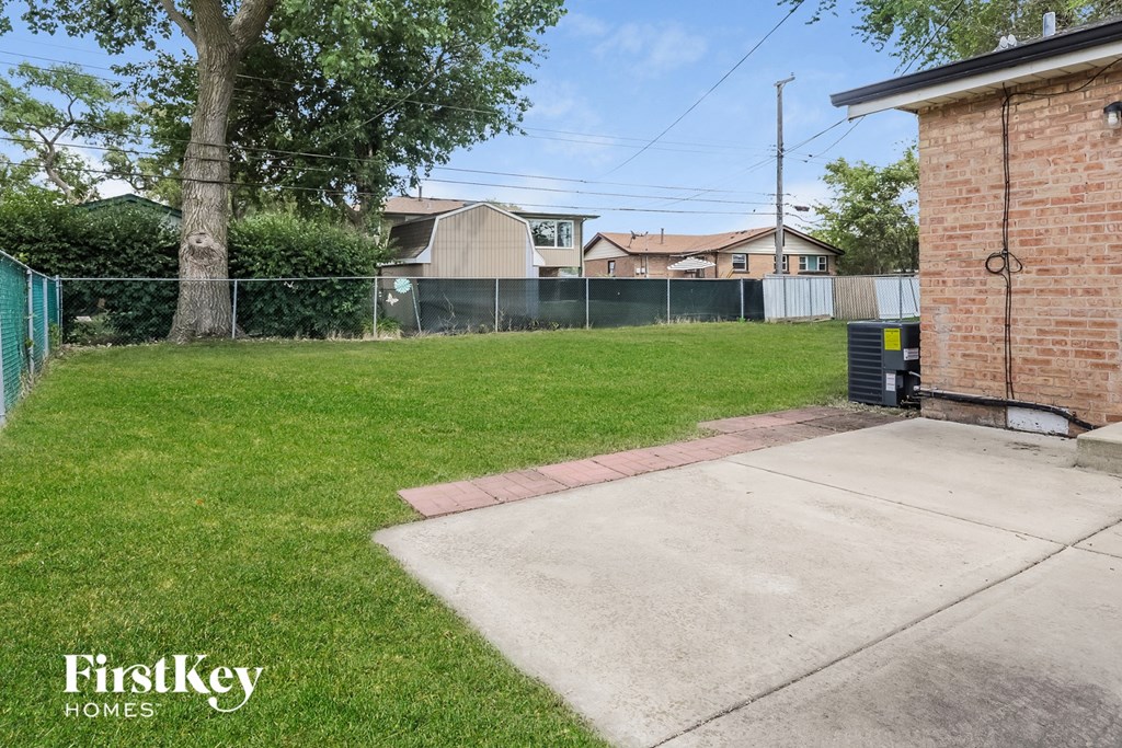 the backyard of a house with a yard and a chain link fence