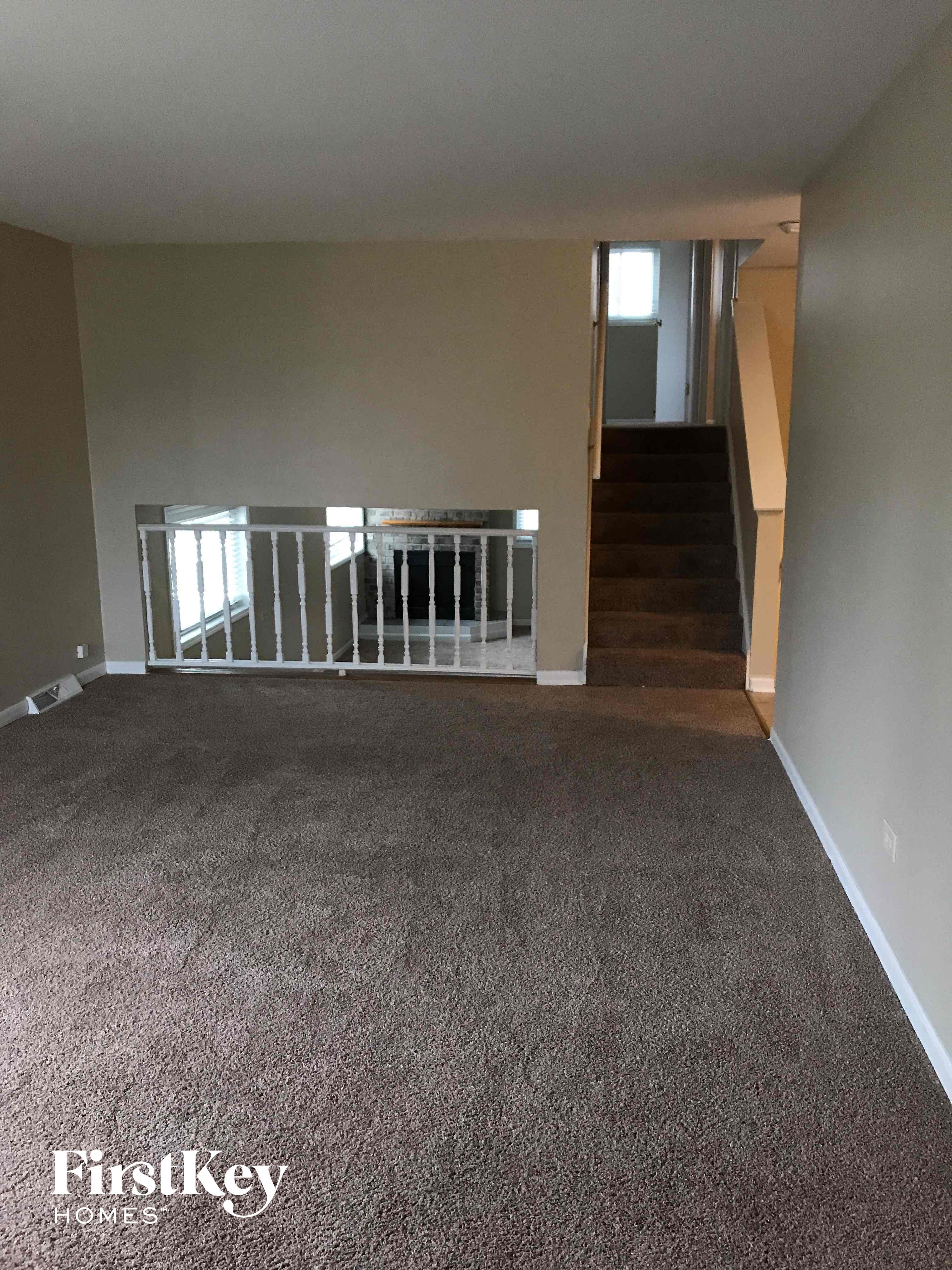 a living room with a carpeted floor and a staircase