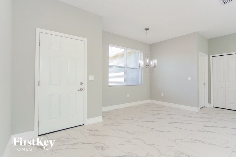 A spacious room with a marble floor and a door on the left.