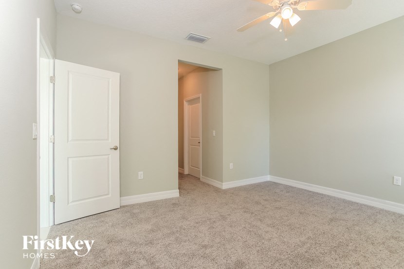 A room with a carpeted floor and a ceiling fan.