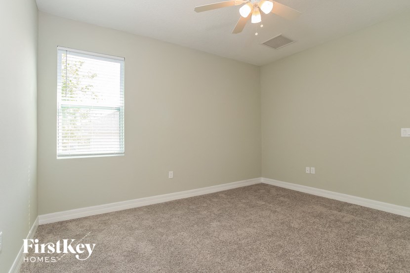 A room with a carpet floor and a ceiling fan.