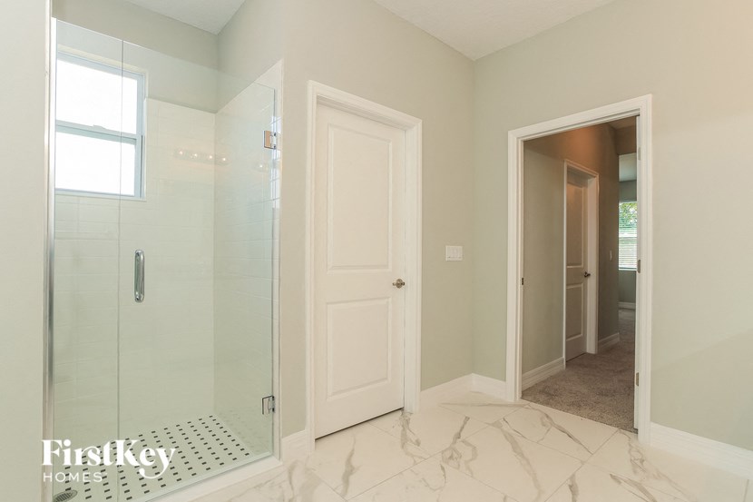A bathroom with a glass shower door and a white door.