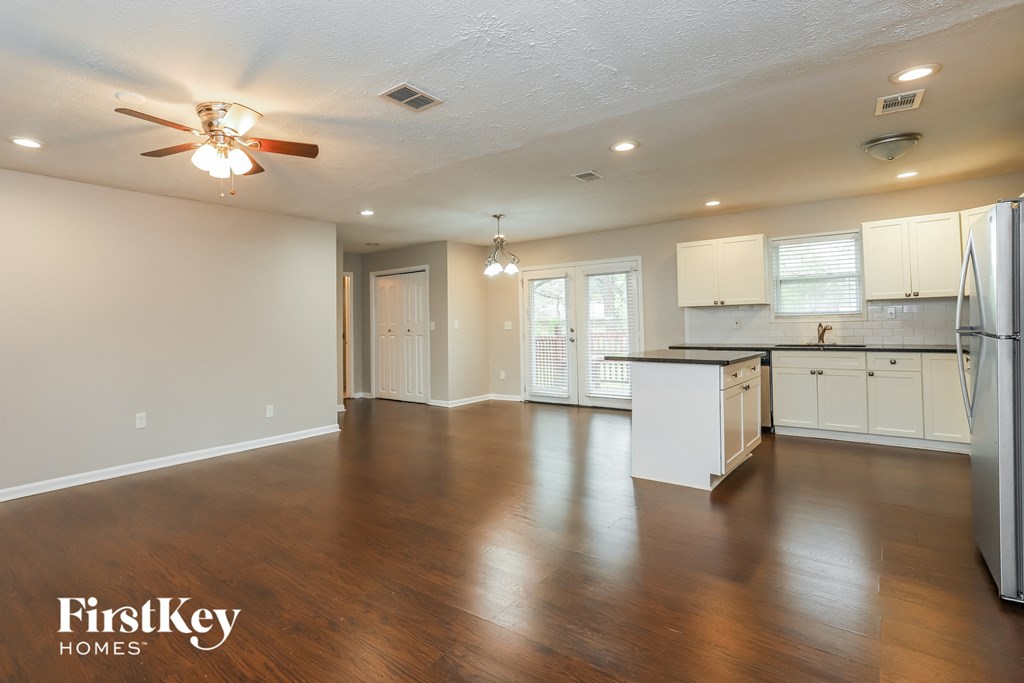A spacious kitchen and living room with wooden floors and white walls.