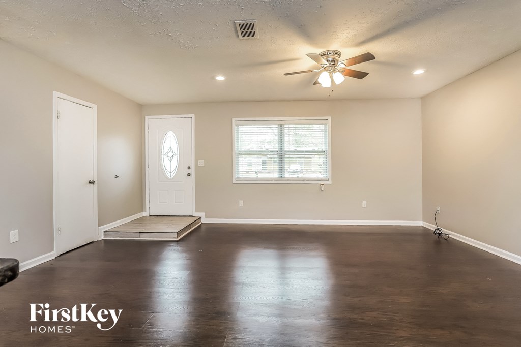 A spacious room with a ceiling fan and a window with blinds.