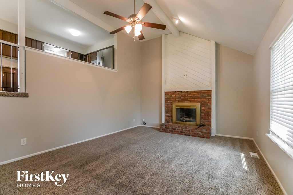 an empty living room with a fireplace and a ceiling fan