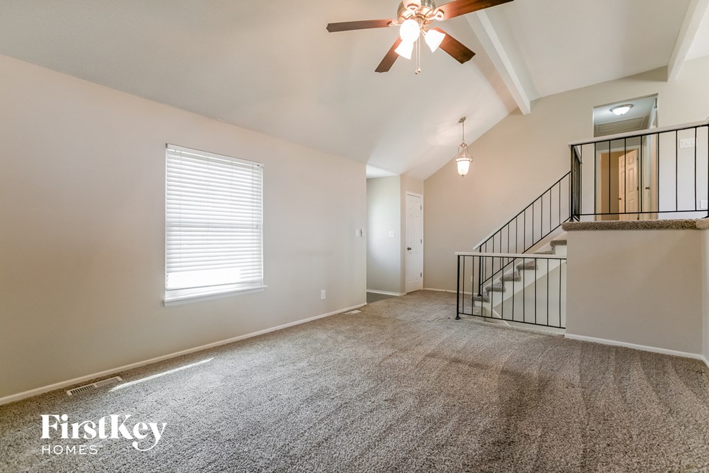 an empty living room with carpeted floors and a ceiling fan
