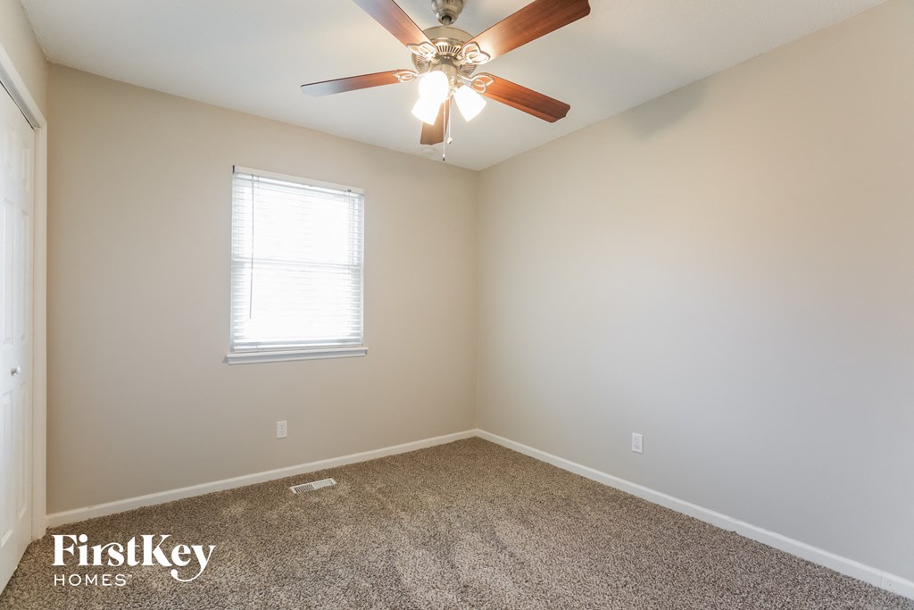 an empty room with a ceiling fan and a window