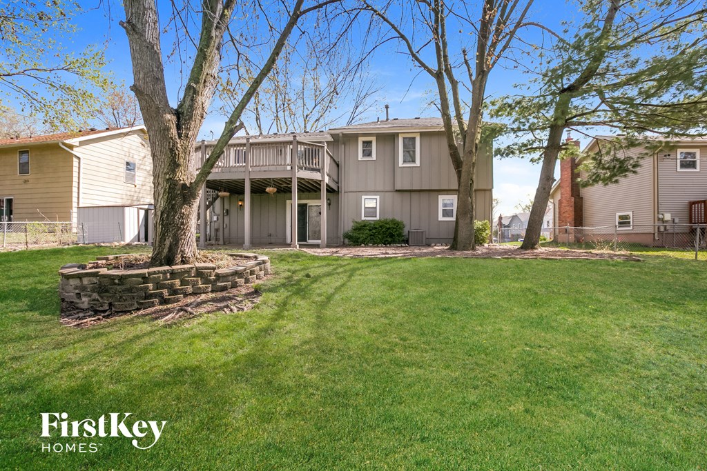 a large lawn in front of a house with trees