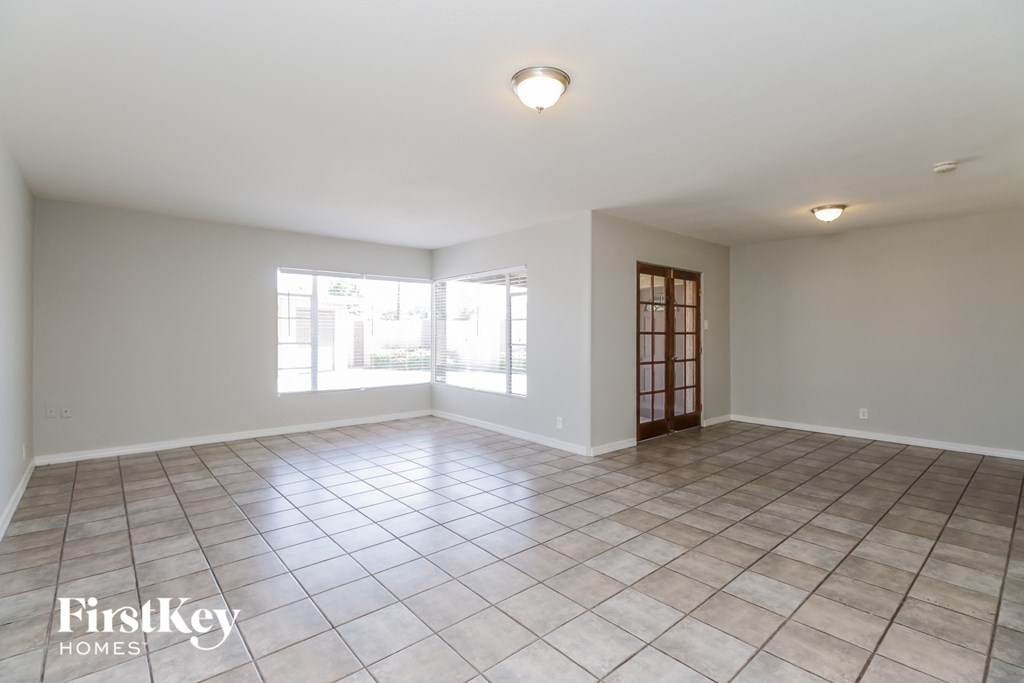 an empty living room with tiled floors and a large window