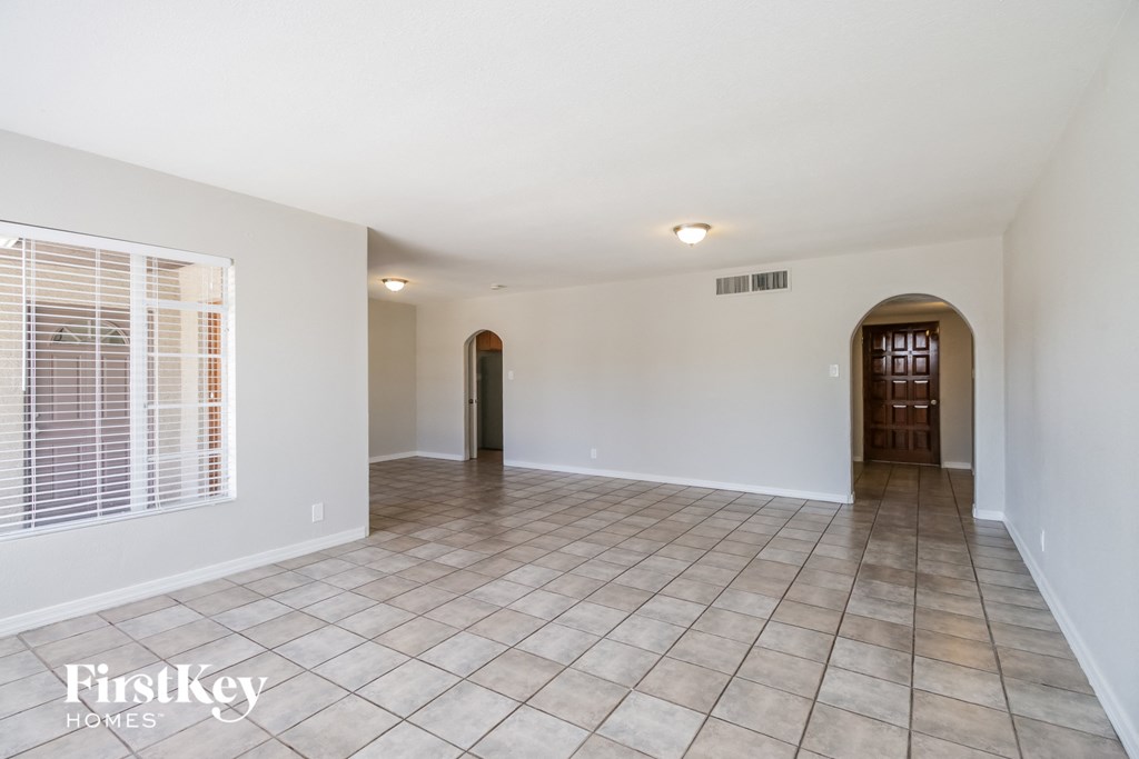 an empty living room with tile flooring and white walls