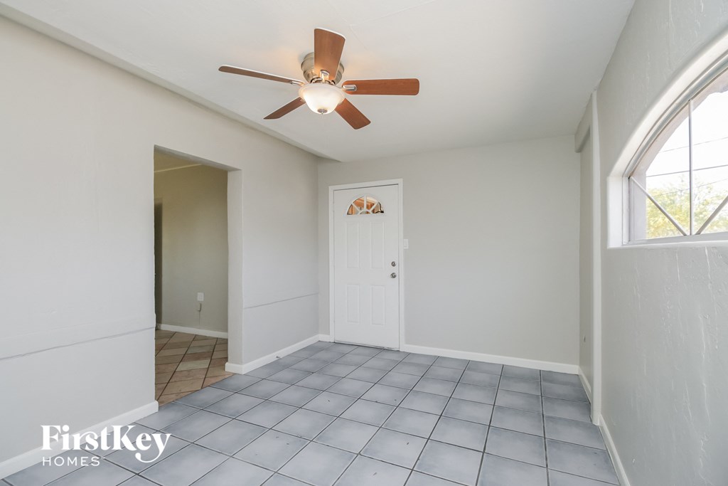 an empty living room with a ceiling fan and a window