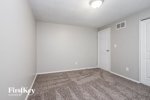 the spacious living room with carpeting and a door to the bedroom