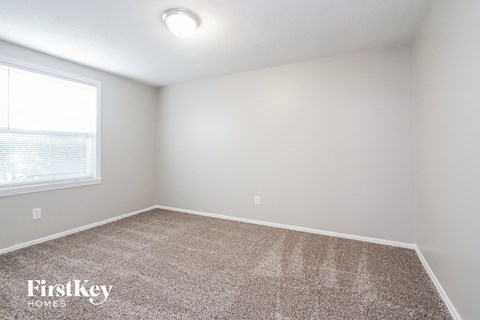 the upstairs bedroom has carpet and a large window