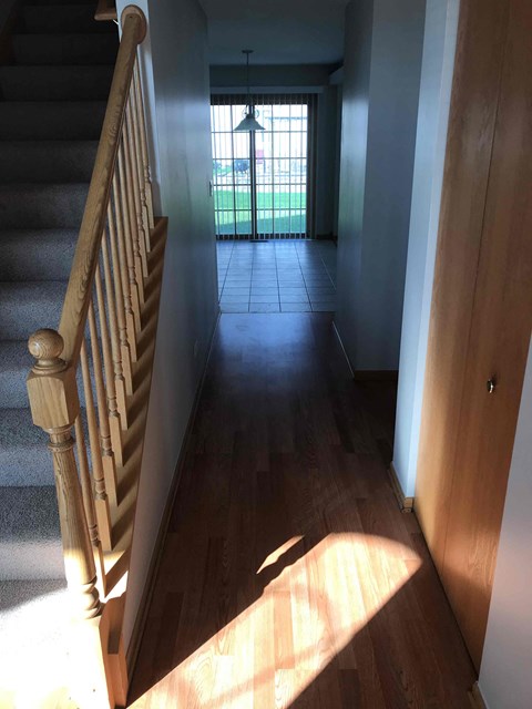 a hallway with a staircase and a door into a house
