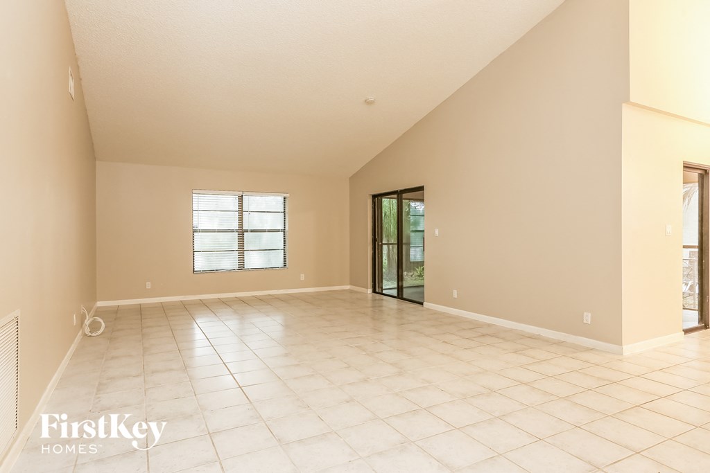 a spacious living room with tiled floors and a sliding glass door
