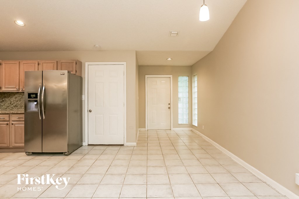 an empty kitchen with a stainless steel refrigerator and cabinets