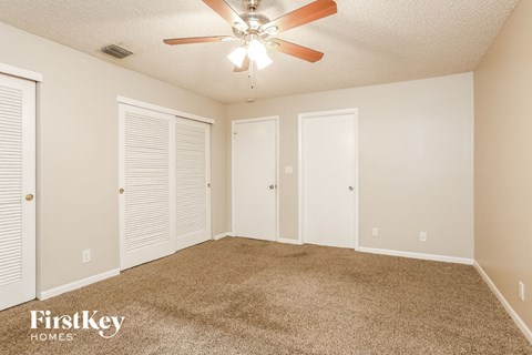 a spacious living room with carpet and a ceiling fan