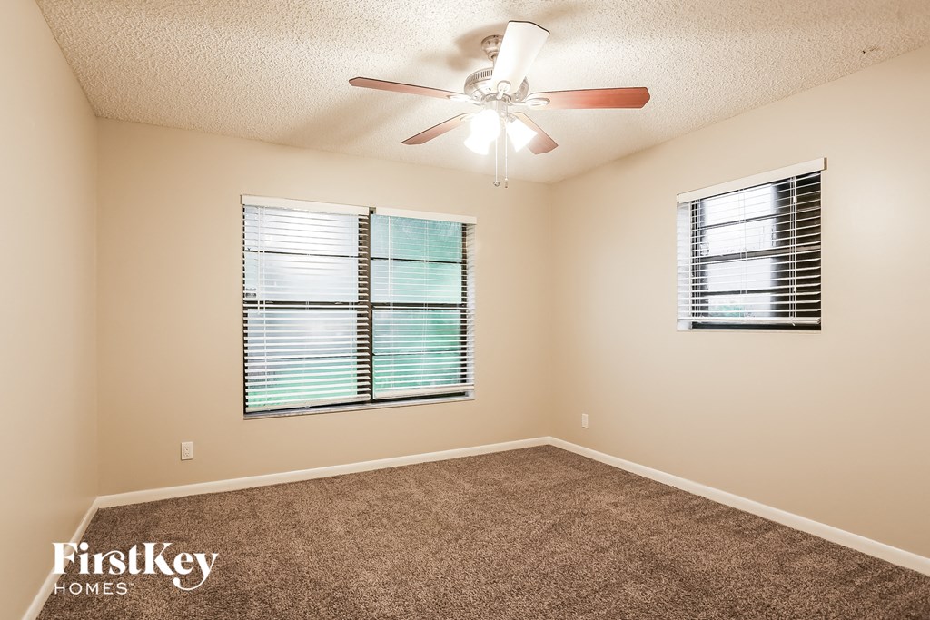 an empty room with a ceiling fan and a window