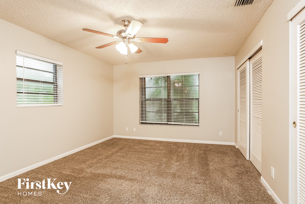 an empty living room with a ceiling fan and a window