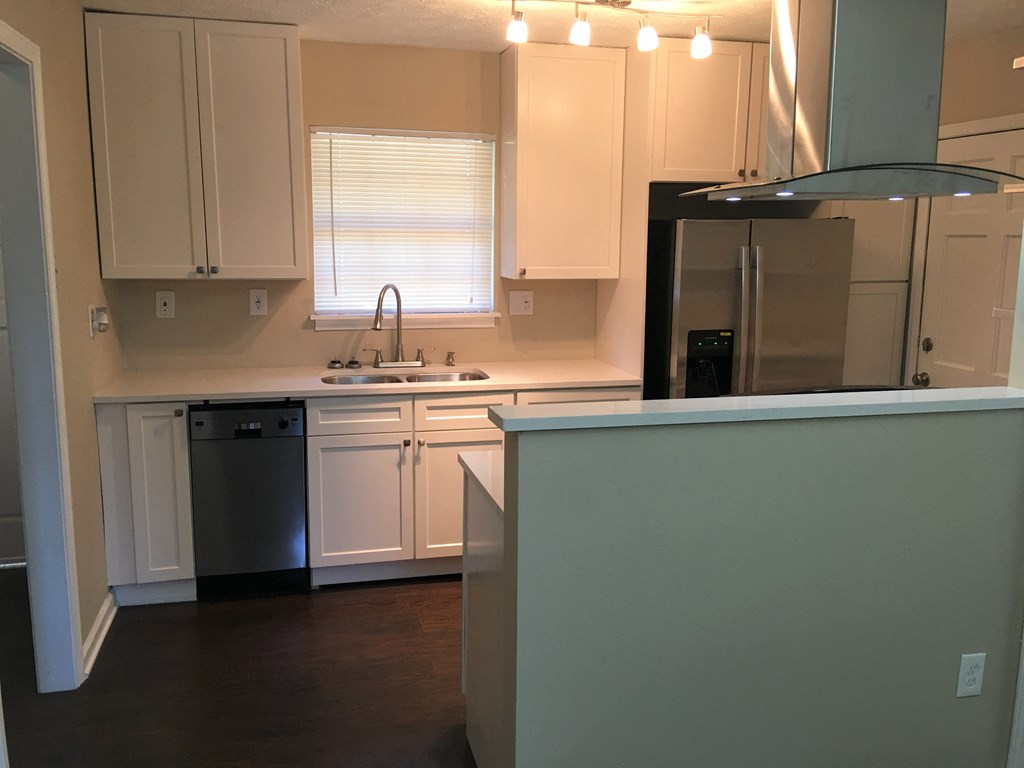 A kitchen with white cabinets and a black fridge.