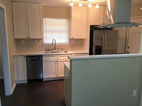 A kitchen with white cabinets and a black fridge.