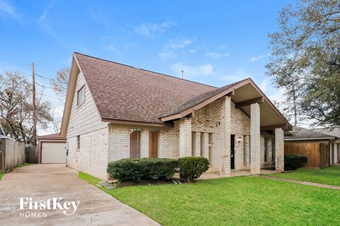 the front of a brick house with a yard and a sidewalk