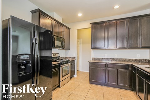 A kitchen with black cabinets and a black refrigerator.