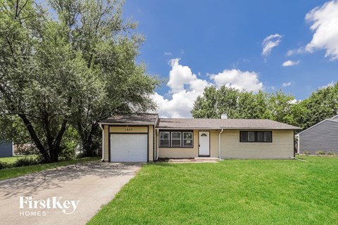 a craftsman style home with a garage and a green lawn