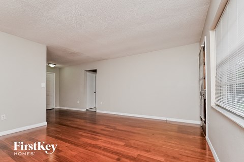 a spacious living room with wood flooring and white walls