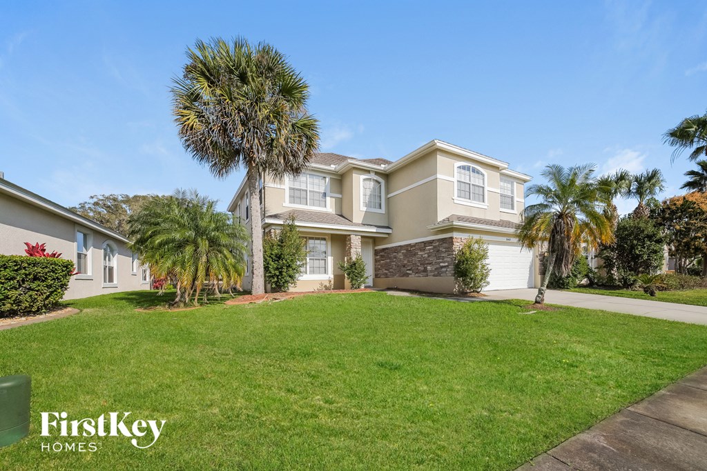 a house with a lawn and palm trees in front of it