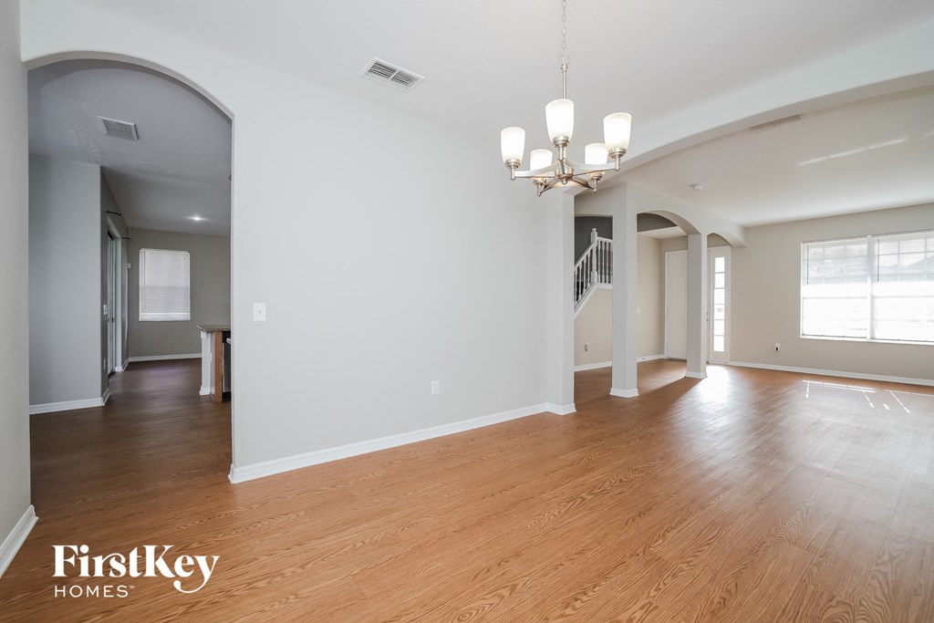 the living room and dining room with hardwood floors and a chandelier
