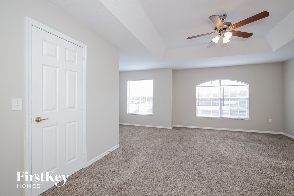 an empty living room with a ceiling fan and a white door