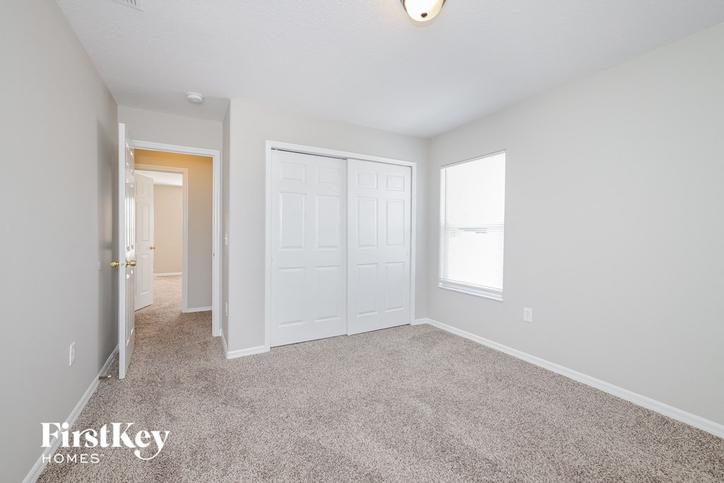 a bedroom with carpet and a door to a closet