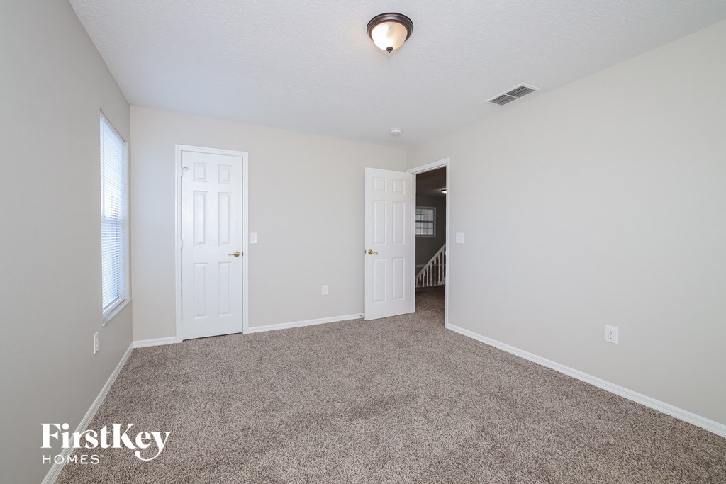 a spacious living room with carpet and a door to the hallway