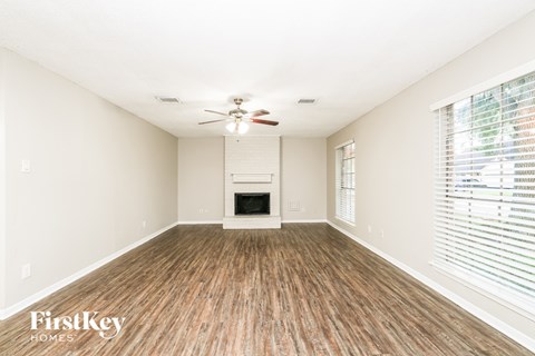 A spacious room with a fireplace and wood flooring.