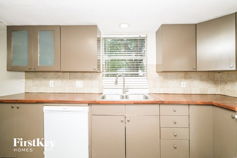 A kitchen with brown cabinets and a white dishwasher.